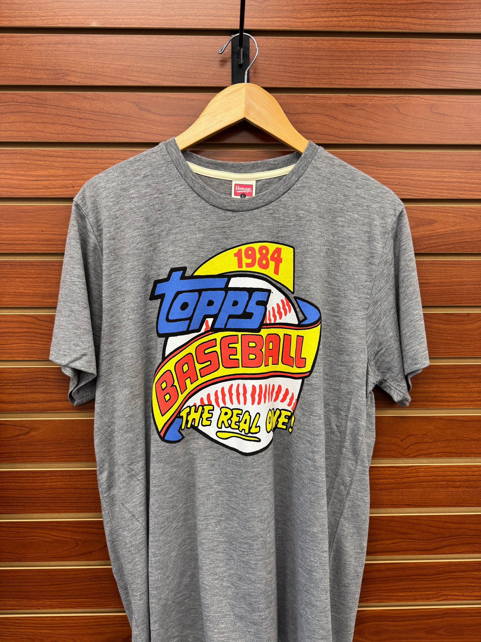 Celebrate baseball history with the Topps Homage 1984 Topps Baseball Grey T-Shirt. Crafted for comfort and style, this shirt features a classic design that honors the iconic 1984 Topps baseball card era. Its soft grey fabric pairs effortlessly with any casual outfit, making it perfect for fans who want to showcase their love for the game while staying comfortable all day. Whether at the ballpark or out with friends, this tee is a timeless addition to your sportswear collection.